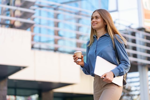 Portrait smiling woman holding laptop and coffee outdoors